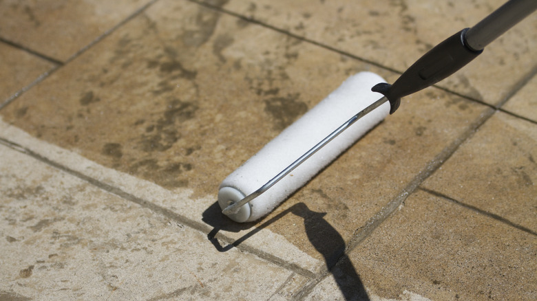 A roller applying stain to a concrete surface