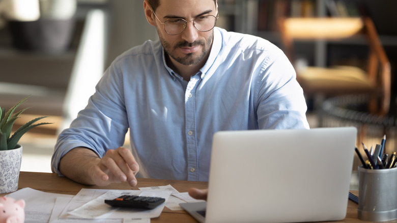 man looking at computer with calculator