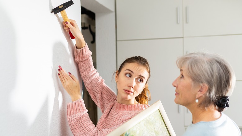 women hammering picture hook 