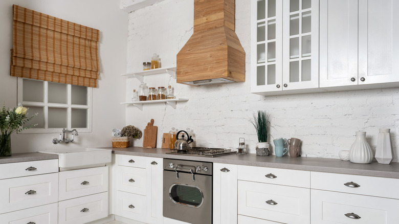 A white kitchen with a wooden vent hood