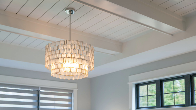 A chandelier hanging from a white shiplap ceiling