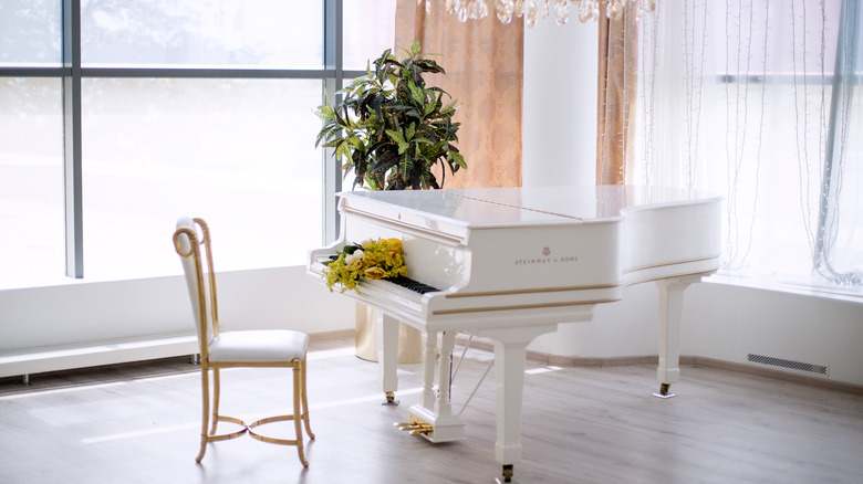 white piano and chair with gold trim