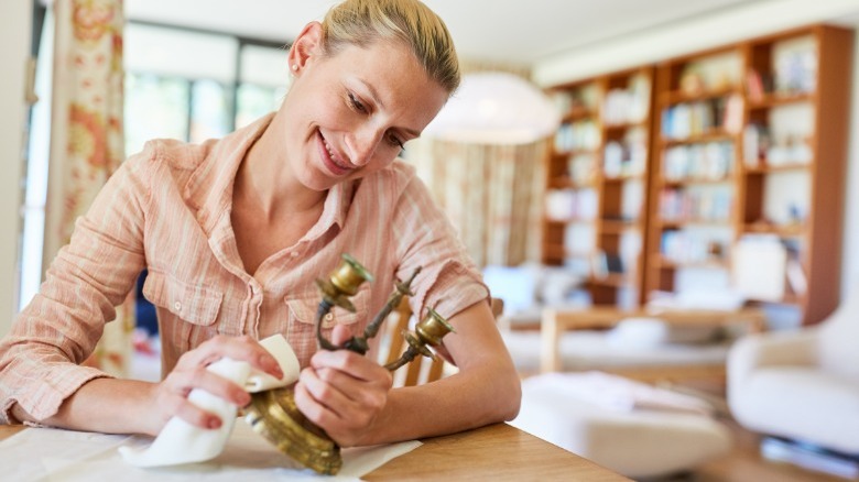 Woman cleaning brass candelabra 