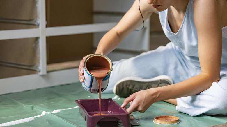 Person pouring paint into tray