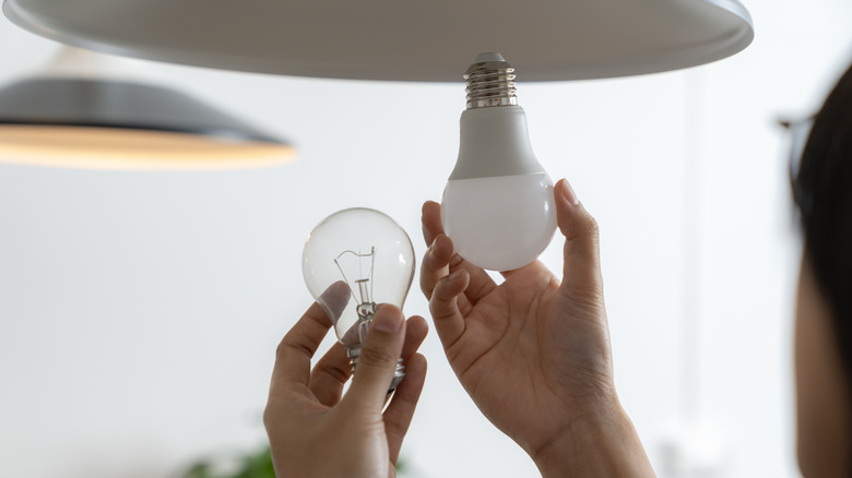 hands changing lightbulb to LED