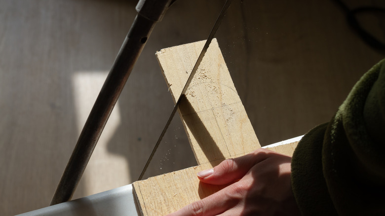 Person cutting wood with a saw