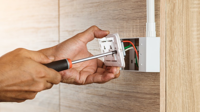 person installing outlet into wall