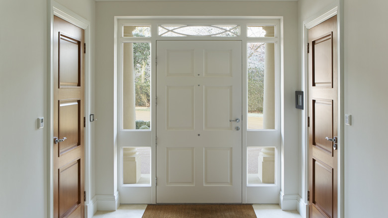 A white front door has large, clear windows on either side