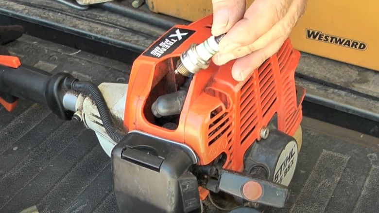 person removing spark plug from Stihl trimmer