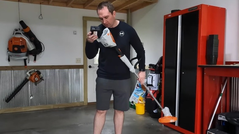 man inserting battery into Stihl weed eater