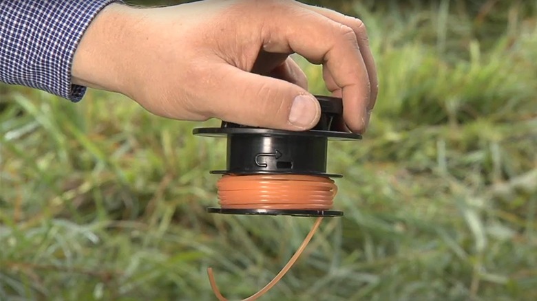 person restringing a trimmer spool