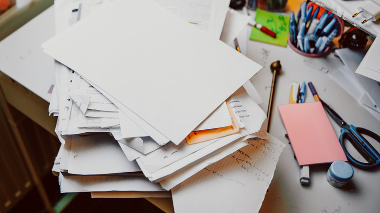 A messy desk is piled full of unorganized papers