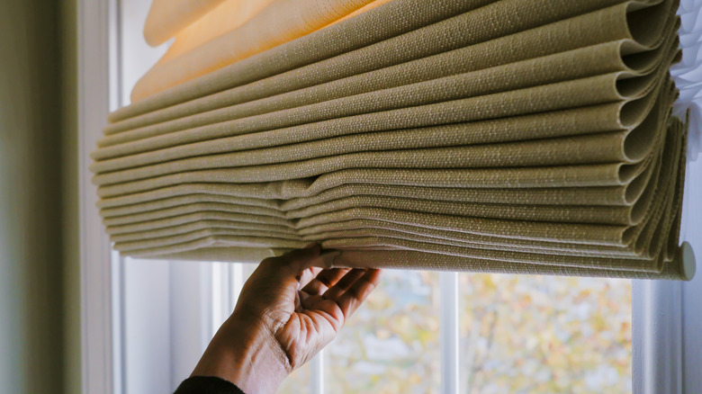 Person raising a version of folding tie up curtains