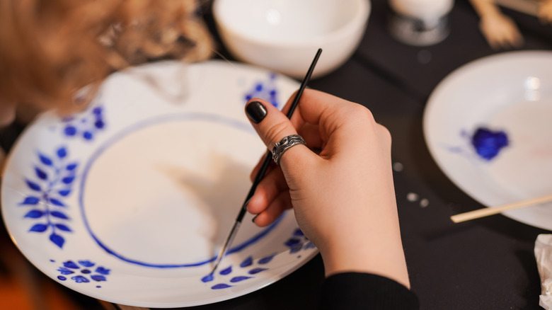 Painting a white plate with blue folk floral design