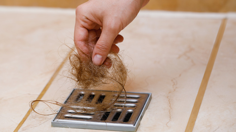 Woman removing hair from shower drain