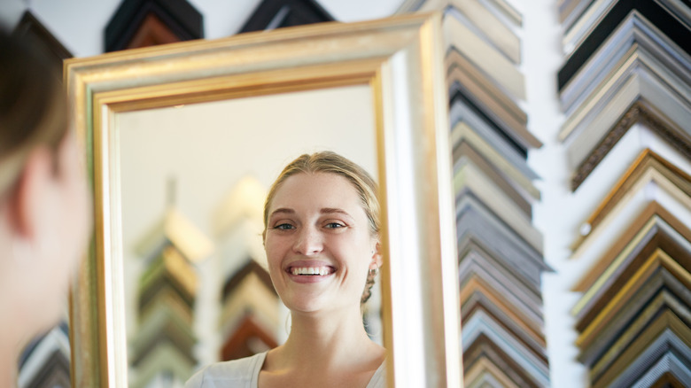 woman smiling into gold mirror