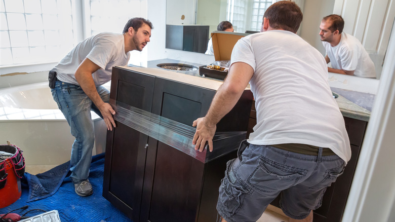 Two men moving a black bathroom vanity into place