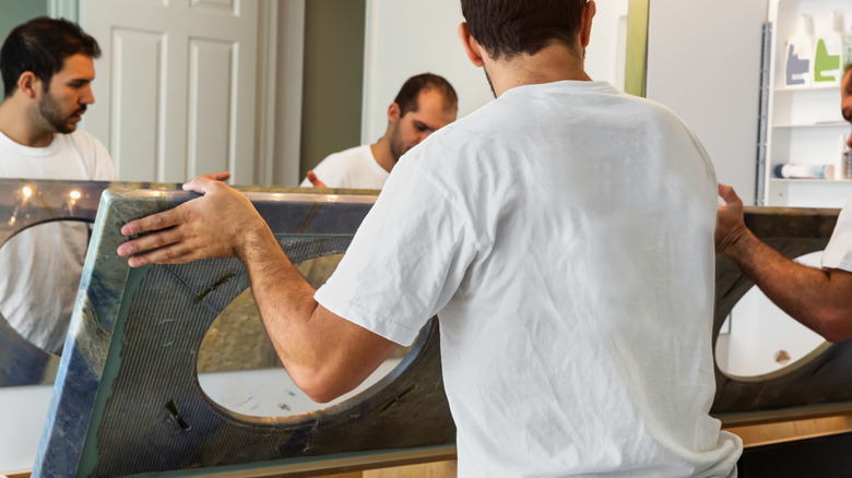 Two men installing a countertop on a new bathroom vanity