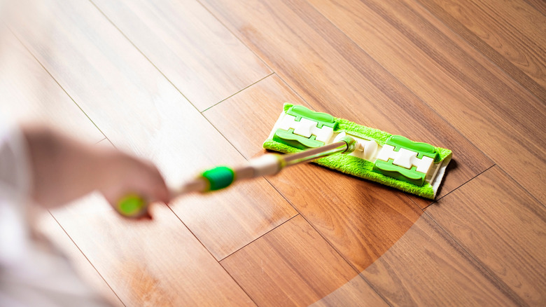 Cleaning a wooden floor with a green microfiber mop