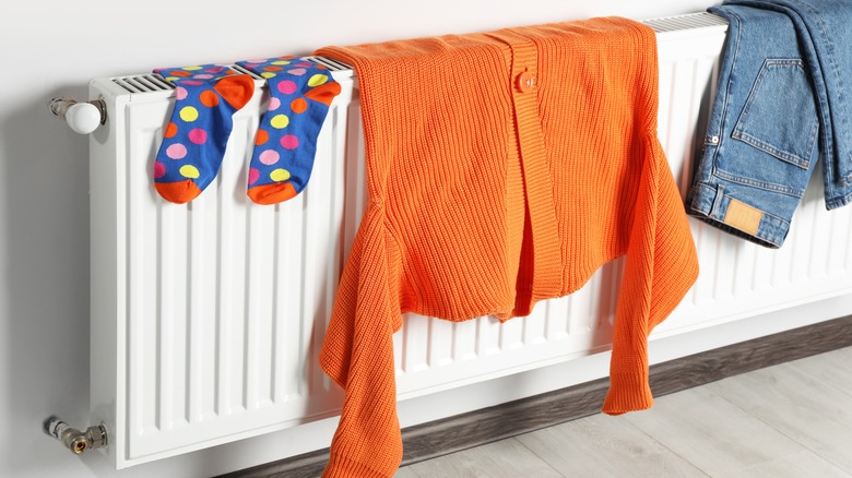 A cardigan, socks, and jeans dry on a radiator.