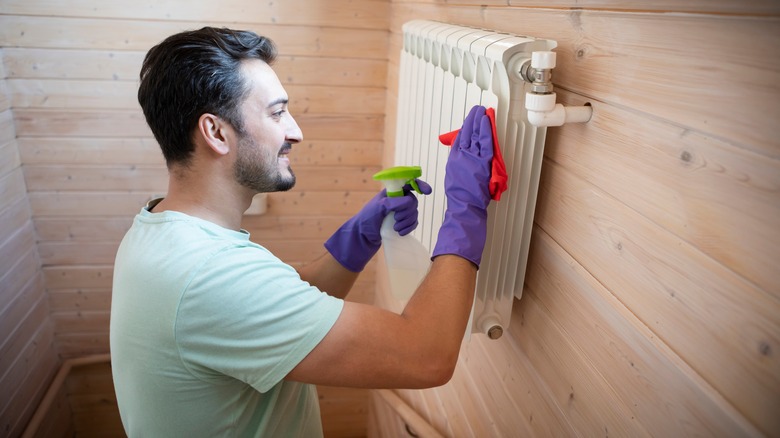 A man cleans a radiator with spray