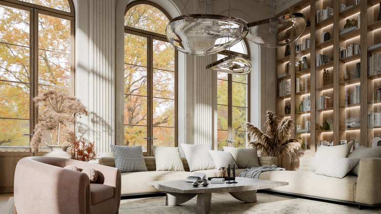 This living room has floor to ceiling bookshelves, tall windows, unique light fixtures, and a large couch.