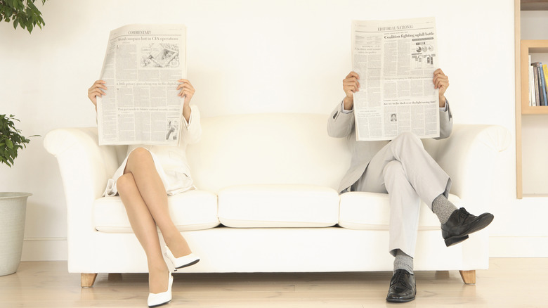 reading newspapers on white couch