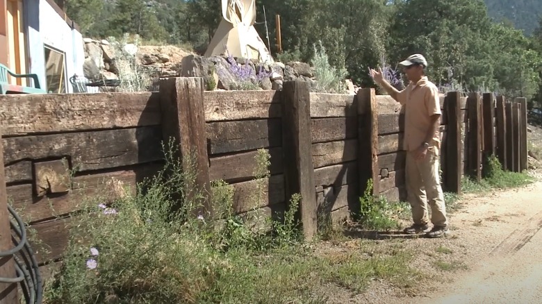 Railroad tie retaining wall with vertical supports