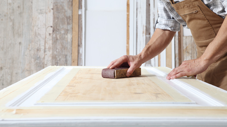 man sanding white door