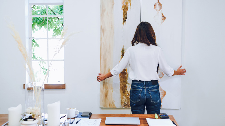 woman fixing artwork on wall