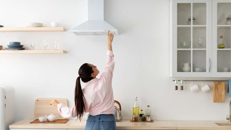 Woman reaching to turn on vent hood