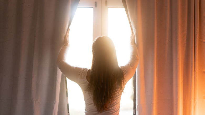 Woman opening curtains