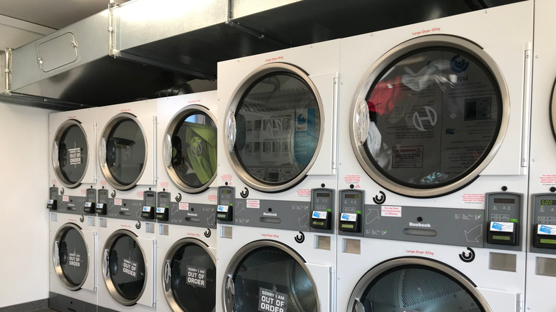 Large and small washing machines inside a laundromat.