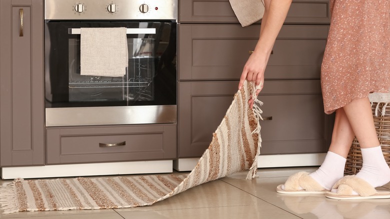 woman picking up kitchen rug