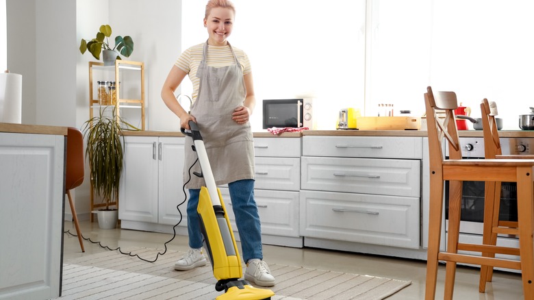 woman vacuuming rug in kitchen