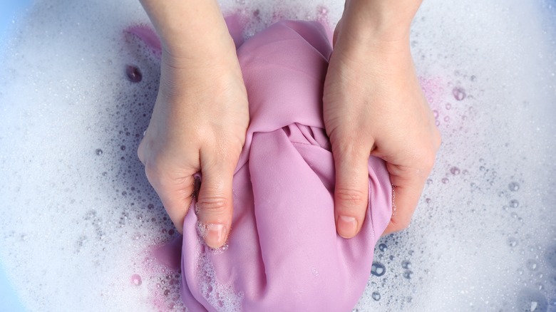 Hands washing fabric in suds