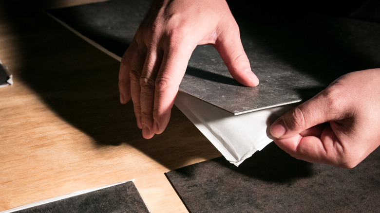 Person removing backing from peel-and-stick tile