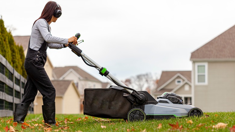 woman mowing lawn in autumn