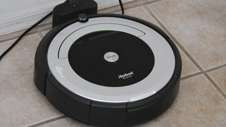 A Roomba sitting in its charging dock on a tile floor