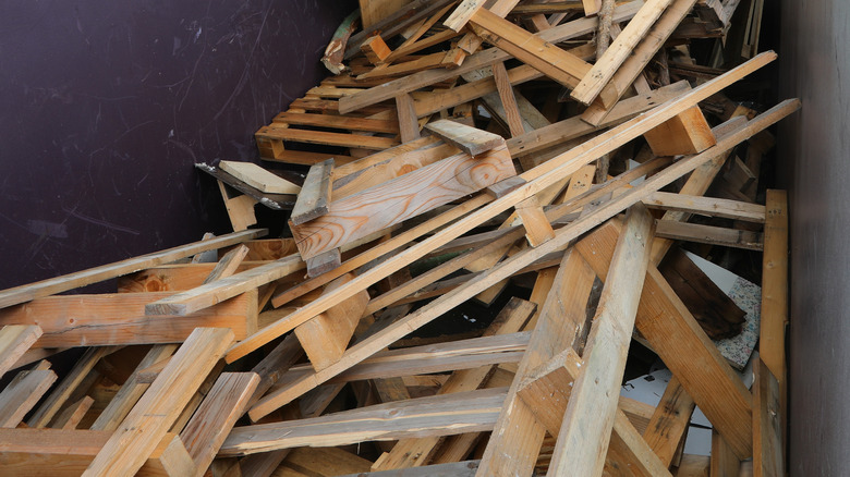 A pile of discarded wood pallets rest against a scratched wall