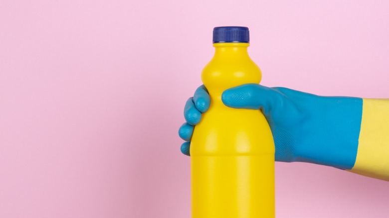 Blue gloved hand holding yellow bottle