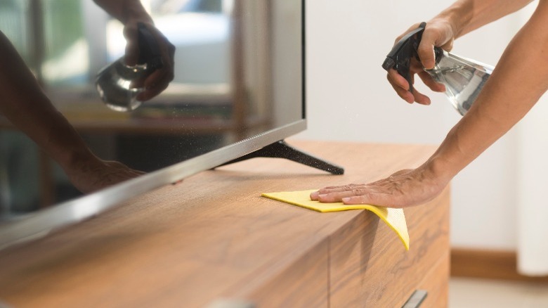 Man cleaning wood tv table 