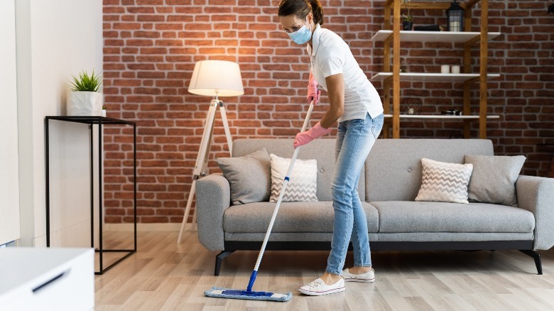 Masked woman cleaning hardwood floors 