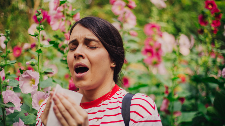 Woman sneezing in flower garden