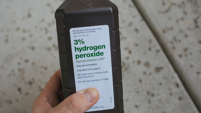 hand holding hydrogen peroxide bottle