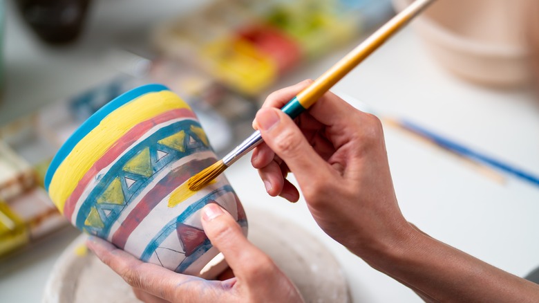 woman painting ceramics with brush