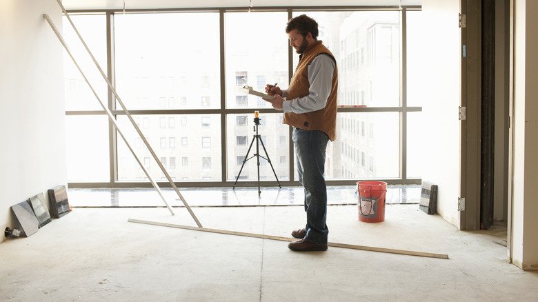 A builder stands on the unfinished floor of a condo still under construction.