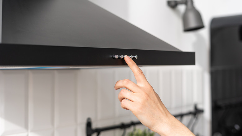 Woman pressing range hood buttons