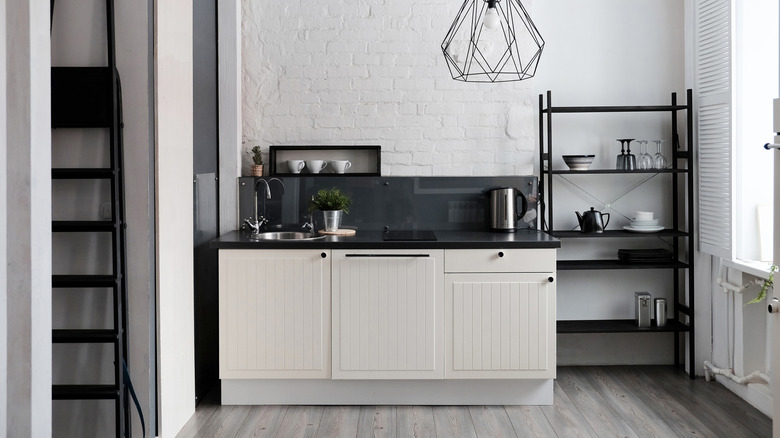 Cream colored cabinets with black countertops and gray wood floors