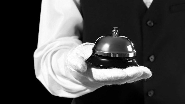 White-gloved hand holding silver bell